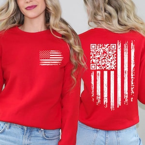 May include: Red sweatshirt featuring a distressed white American flag design on the front and a QR code flag design on the back. The long-sleeved top is made of a soft material and is suitable for casual wear.