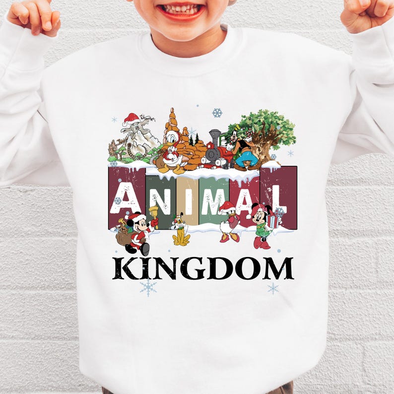 A white sweatshirt with a colorful graphic design featuring various Disney characters and the word "ANIMAL KINGDOM" printed on it.