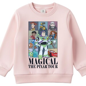 A pink sweatshirt with a graphic design featuring characters from the animated film "Pixar's Magical The P Pixar Tour".