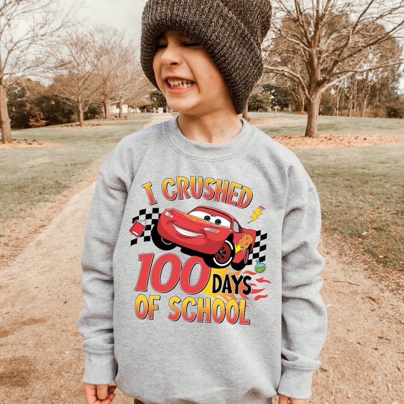 a young boy wearing a gray sweatshirt with a cartoon character on it