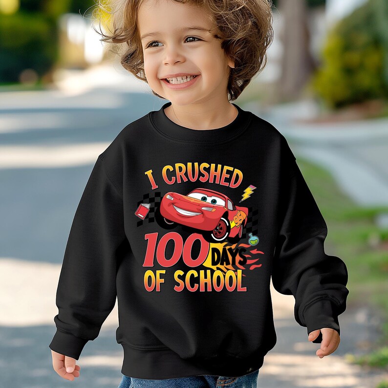 a young boy wearing a black sweatshirt with cars printed on it