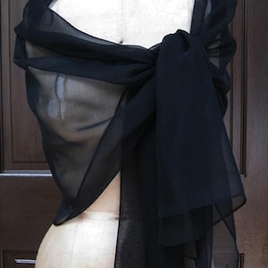 May include: A black sheer shawl draped over a dress form. The shawl is made of a lightweight fabric and has a flowing, elegant look.