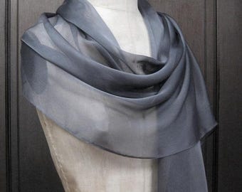May include: A sheer black scarf draped over a dress form. The scarf is made of a lightweight fabric and has a subtle ombre effect.