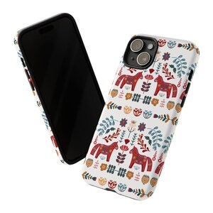May include: A white phone case with a colorful Scandinavian folk art design featuring red horses, flowers, and leaves. The case has a black border and a cutout for the camera lens.