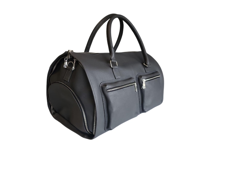 May include: A dark gray duffel bag with two exterior zippered pockets and a zippered side pocket. The bag has two top handles and a detachable shoulder strap. The hardware is silver-toned.