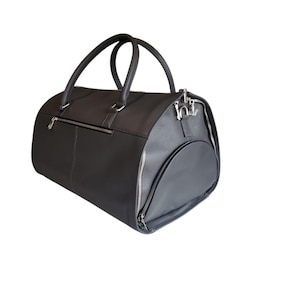 May include: A black duffel bag with a rounded shape, featuring two top handles and a side pocket. The bag has a zipper closure and silver-colored hardware. The material appears to be leather or a leather-like material.