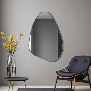 May include: An irregular, pebble-shaped wall mirror with a thin, matte blue frame. The mirror features a smooth, organic outline that deviates from traditional geometric shapes, providing a reflective surface with a distinct, asymmetrical contour.