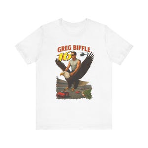 May include: White t-shirt with a graphic of a man riding an eagle above a race track. The graphic includes the text "GREG BIFFLE 16" in yellow and red. A helicopter is also in the graphic.