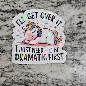 May include: A white unicorn with a rainbow mane and tail is lying down with its eyes closed. The unicorn is on a sticker with the text "I'll get over it I just need to be dramatic first".