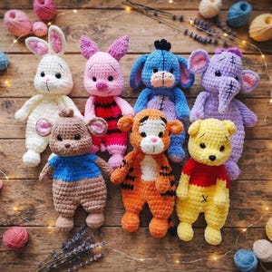 May include: A collection of seven crocheted plush toys including a white rabbit, a pink piglet, a blue donkey, a purple elephant, a brown bear with a blue shirt, an orange tiger, and a yellow bear with a red shirt, surrounded by yarn balls.