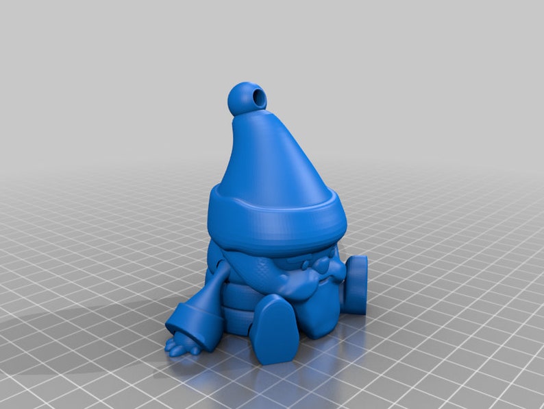 May include: A blue gnome figurine with a pointed hat, scarf, and round nose. The gnome is sitting with its legs extended and arms resting on its knees. The figurine has a small loop at the top of the hat.