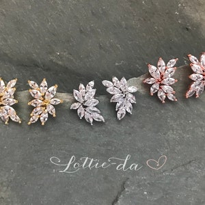 May include: Four pairs of earrings with a floral design. The earrings are made of gold, silver, and rose gold. Each earring features a cluster of clear cubic zirconia stones.