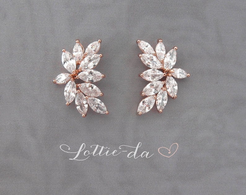May include: A pair of rose gold earrings with a cluster of clear cubic zirconia stones in a leaf design.