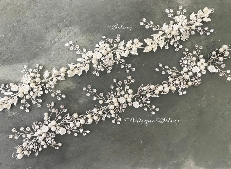 Pu&ograve; includere: Quattro pettini per capelli argentati con decorazioni di perle e cristalli. I pettini sono disposti in fila su uno sfondo grigio. Il testo "Silver" e "Antique Silver" &egrave; visibile nell'immagine.