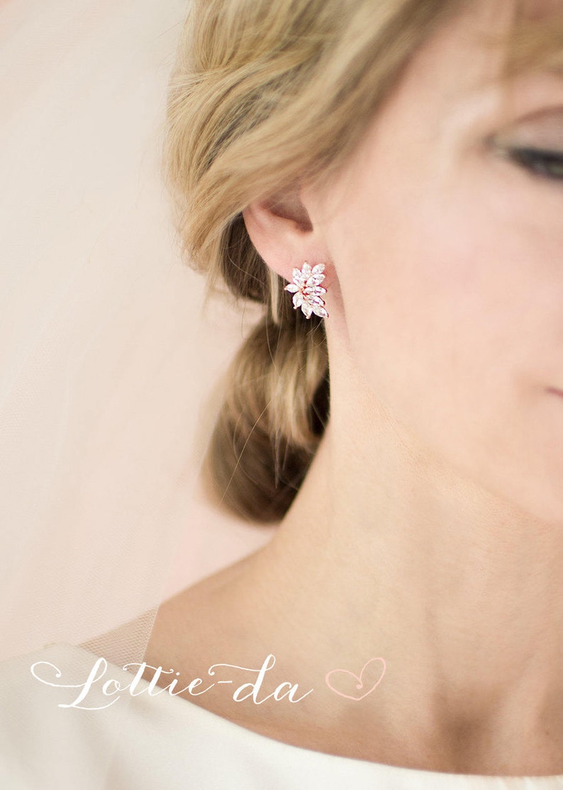 May include: Rose gold earrings with a cluster of clear cubic zirconia stones in a floral design.