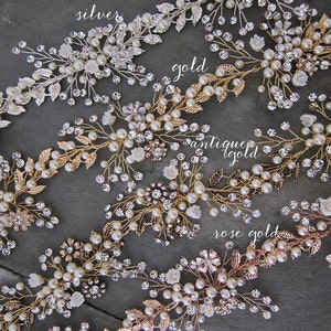 Pu&ograve; includere: Cinque pettini per capelli con decorazioni di perle e cristalli in finiture argento, oro, oro antico e oro rosa. I pettini sono disposti in fila su uno sfondo grigio.