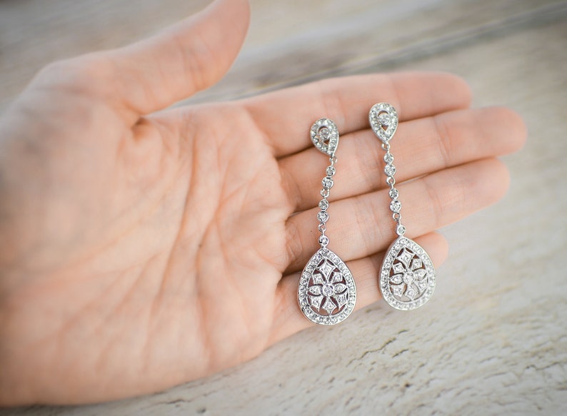 Pu&ograve; includere: Un paio di orecchini a goccia d'argento con un design floreale e cristalli trasparenti.