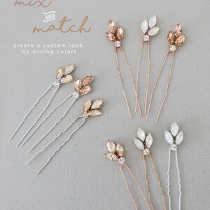 May include: Set of six hair pins with crystal embellishments in three colors: champagne, ivory, and clear. The pins are designed to look like leaves and are perfect for adding a touch of sparkle to any hairstyle.