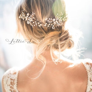 Pu&ograve; includere: Una donna con i capelli biondi indossa un abito bianco di pizzo con un fermaglio per capelli in oro e perle. Il fermaglio per capelli ha un design floreale con foglie e perle.