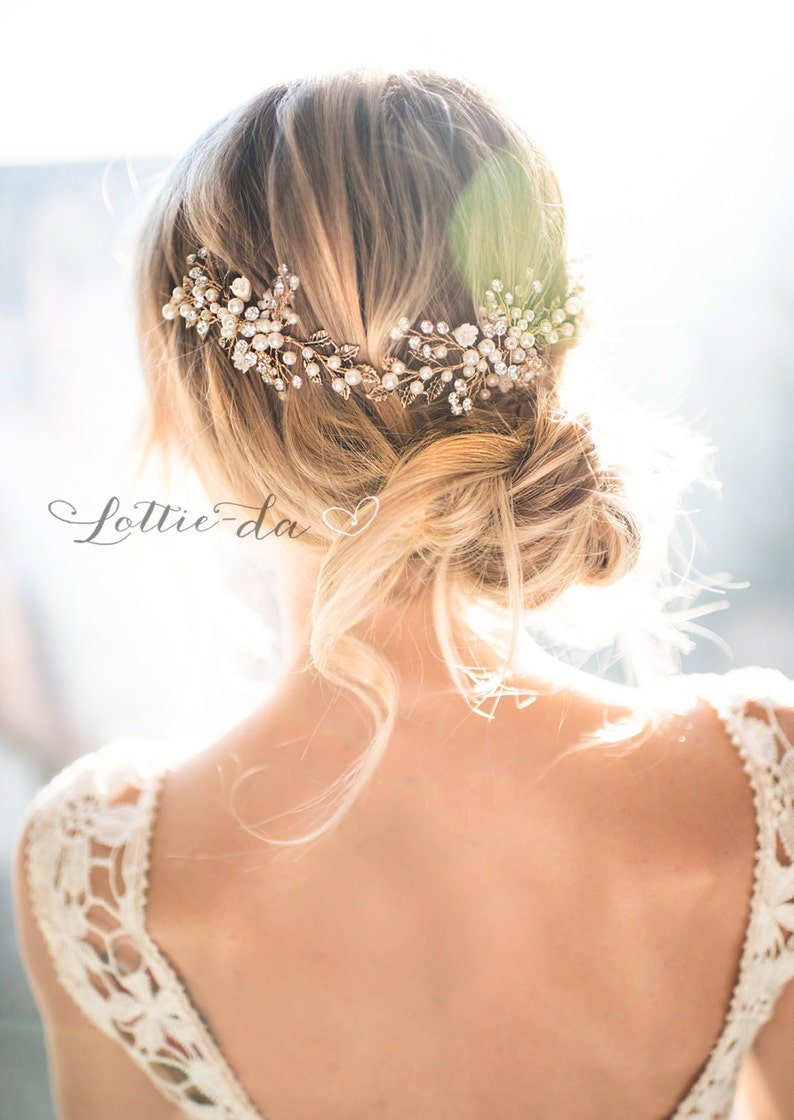 Pu&ograve; includere: Una donna con i capelli biondi indossa un abito bianco di pizzo con un fermaglio per capelli in oro e perle. Il fermaglio per capelli ha un design floreale con foglie e perle.