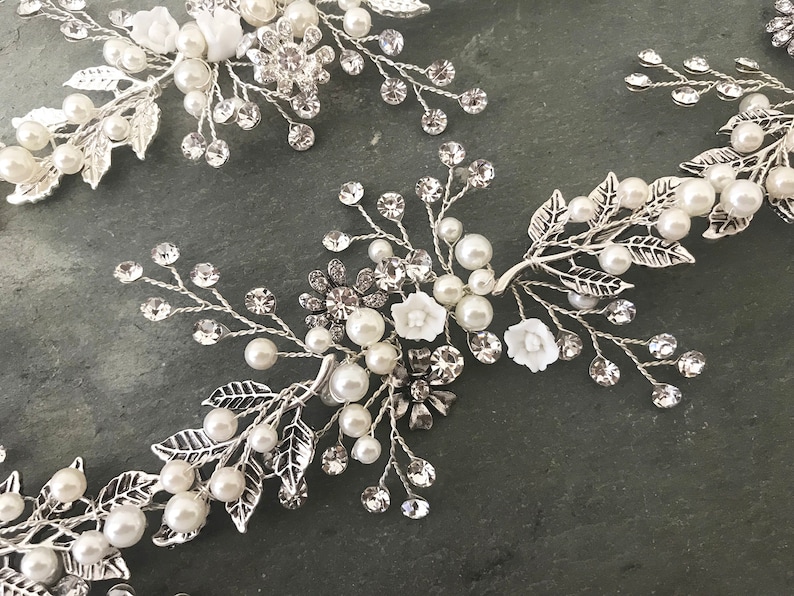 Pu&ograve; includere: Pettine per capelli argentato con decorazioni di perle bianche e cristalli a forma di fiori.