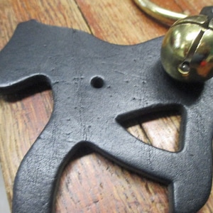 May include: Black leather horse shaped doorstop with a brass bell attached to the top.