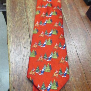 May include: Red Christmas-themed necktie with a repeating pattern of Santa Claus, reindeer, and Christmas trees. The tie is made of a smooth fabric and is suitable for festive occasions.