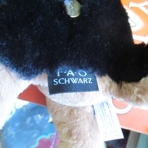 May include: Close-up of a plush toy with black fur on top and tan fur underneath. A black tag with the text "F.A.O. SCHWARZ" is attached. A gold-colored tag is also visible.