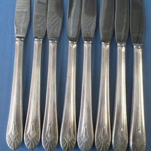 May include: Eight silver dinner knives with ornate handles. The knives have a simple, elegant design.