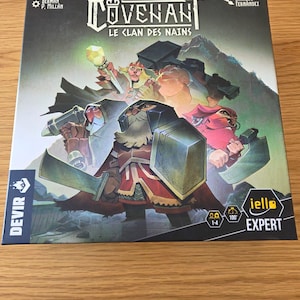 Peut inclure: Une boîte de jeu de société carrée intitulée Covenant Le Clan des Nains illustrée avec quatre personnages nains en armure dans un décor montagneux. La boîte comporte le logo Devir, la marque Iello Expert et des icônes de joueurs.