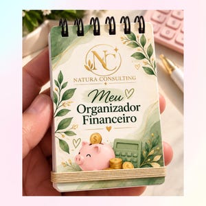 Peut inclure: Un carnet à spirales avec une couverture crème ornée de feuilles aquarelles vertes, un logo doré et le texte Natura Consulting Meu Organizador Financeiro. Le motif inclut une tirelire rose, des pièces dorées et une calculatrice verte.