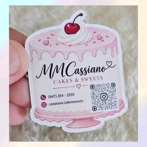 Może przedstawiać: Wykrawana naklejka w kształcie różowego tortu z białym lukrem, czerwoną wisienką i małymi serduszkami. Zawiera napis MM Cassiano CAKES & SWEETS, numer telefonu (647) 254-2339, nazwę użytkownika na Instagramie oraz kod QR do zeskanowania.