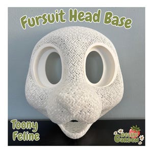 May include: A white, 3D-printed fursuit head base with large eye openings and a feline-like snout. The text "Fursuit Head Base" is at the top, and "Toony Feline" is at the bottom. The Nelly's Garden logo is in the bottom right corner.