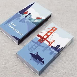 May include: Two matchboxes with San Francisco themed illustrations. One features the city skyline and the text "SAN FRANCISCO". The other depicts the Golden Gate Bridge. Both have blue and white designs.
