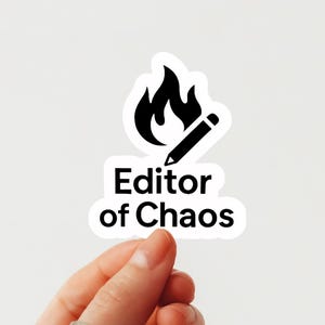 May include: A white sticker featuring a black flame and pencil graphic, with the words "Editor of Chaos" in black. The sticker is held by a hand against a white backdrop.