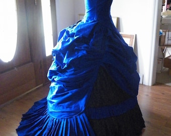 Könnte beinhalten: Ein blaues und schwarzes Ballkleid mit vollem Rock und einem taillierten Oberteil. Der Rock besteht aus mehreren Stofflagen und hat einen gekräuselten Saum. Das Oberteil ist ärmellos und hat einen herzförmigen Ausschnitt.