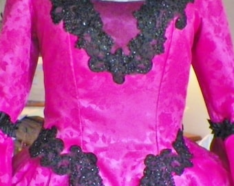 May include: A pink satin dress with a black lace bodice and a black velvet bow at the neckline.