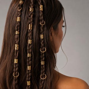 Peut inclure: Gros plan sur des cheveux bruns tressés ornés de manchons et d'anneaux dorés. Les accessoires capillaires présentent divers motifs, tels que des motifs ajourés et des anneaux circulaires, ajoutant une touche décorative à la coiffure.