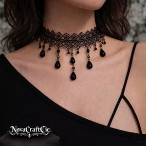 May include: Black lace choker necklace with teardrop-shaped beads. The intricate design features a delicate pattern around the neck, with beaded dangles adding a touch of elegance. A stylish accessory for special occasions.
