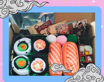May include: A gift box filled with sushi-themed socks. The socks are in the shape of sushi rolls and are made of a soft, plush material. The box also includes a small plastic container with a variety of sushi toppings.