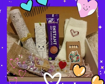 May include: A gift box filled with various items, including a roll of coloring paper, a Cadbury Instant Hot Chocolate packet, a pair of socks with a heart design, and a small box with a unicorn sticker. The box is decorated with heart and star graphics.