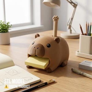 May include: A brown capybara-shaped desk organizer featuring a slot for a stack of yellow sticky notes and a vertical pen holder topped with a paw print design. The text "STL MODEL" and "DIGITAL PRODUCT" is visible on the lower left side.