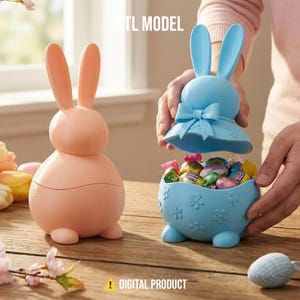Puede incluir: Dos recipientes con forma de conejito de Pascua. Uno es de color melocotón, el otro es azul claro y está abierto, revelando caramelos envueltos. El recipiente azul tiene un lazo y detalles de flores. El texto "STL MODEL" y "DIGITAL PRODUCT" son visibles.