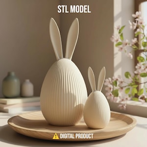 Könnte beinhalten: Zwei cremefarbene Osterhasenfiguren, eine große und eine kleine, stehen auf einem Holztablett. Die Figuren haben lange Ohren und eiförmige Körper mit vertikalen Linien. Der Text "STL MODEL" und "DIGITAL PRODUCT" sind sichtbar.