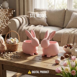 Könnte beinhalten: Zwei rosa hasenförmige Pflanzgefäße stehen auf einem Holztisch, zusammen mit einem Korb mit Ostereiern und einer Schüssel mit Schokoladeneiern. Die Pflanzgefäße haben offene Oberteile für Pflanzen oder Dekorationen. Der Text "STL MODEL" und "DIGITAL PRODUCT" ist ebenfalls vorhanden.