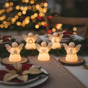 May include: Five glowing angel figurines with different symbols, including a star, heart, and Christmas tree, sit on wooden coasters. The angels are arranged on a table with a festive Christmas theme, with a blurred background of lights.