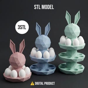 Op de afbeelding: Drie geometrische konijnvormige eierhouders in roze, blauw en groen, elk met witte eieren. De houders hebben een gelaagd ontwerp met eivormige uitsparingen. De tekst "STL MODEL", "3STL" en "DIGITAL PRODUCT" is inbegrepen.