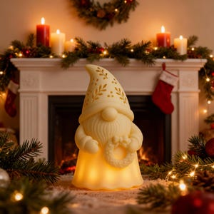 May include: A cream-colored gnome figurine with a patterned hat and a beard, holding a wreath. The gnome is illuminated from within, creating a warm glow. The background includes a fireplace, candles, and Christmas decorations.
