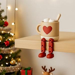 May include: A whimsical beige mug with a red heart, marshmallows, and a spoon. The mug has articulated red legs and feet, giving it a playful appearance. A festive holiday decoration.