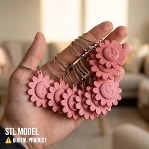 May include: A hand holding a collection of pink flower-shaped keychains. Each keychain has a letter or number in the center. The keychains are attached to silver rings. The text "STL MODEL" and "DIGITAL PRODUCT" is visible at the bottom.